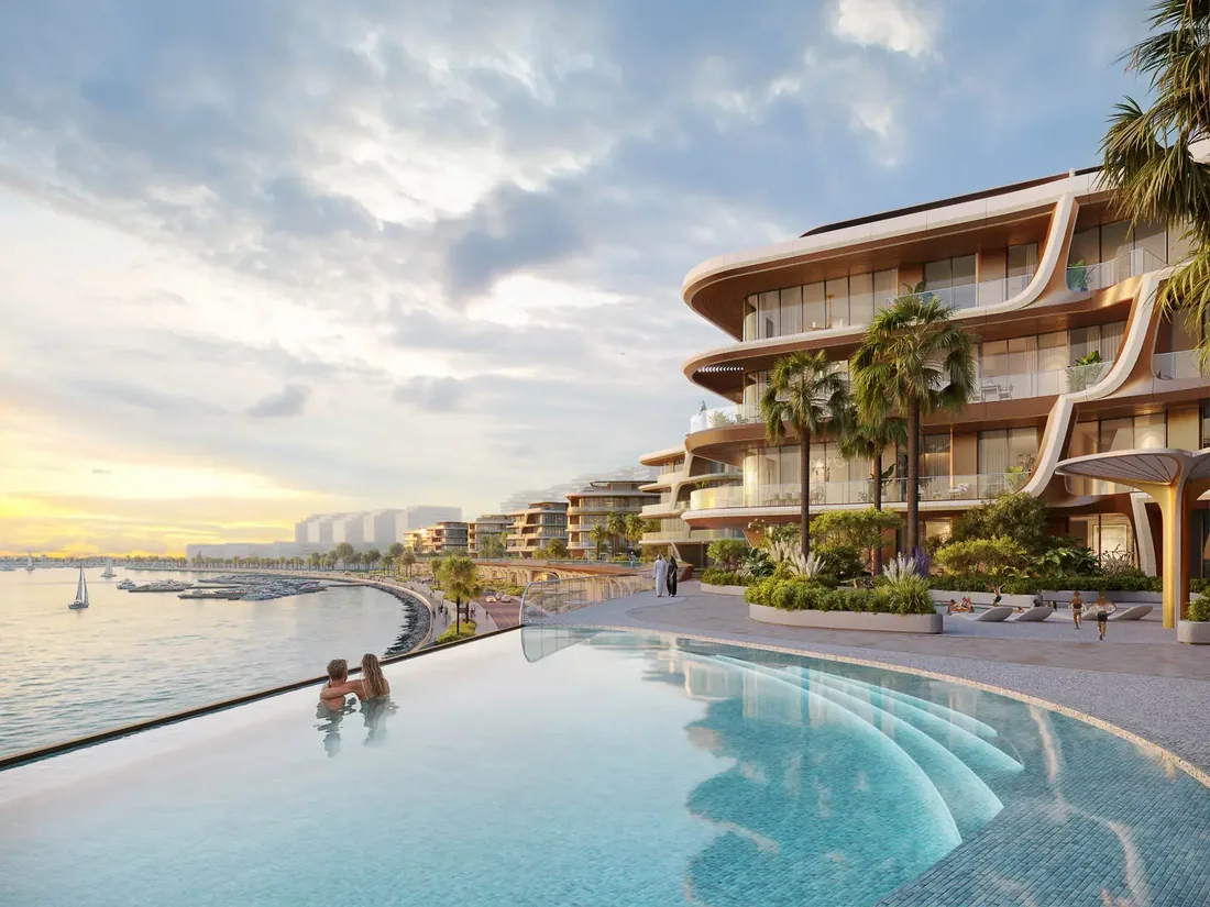 Infinity pool at dusk meeting the calm water beyond, with The Grove behind